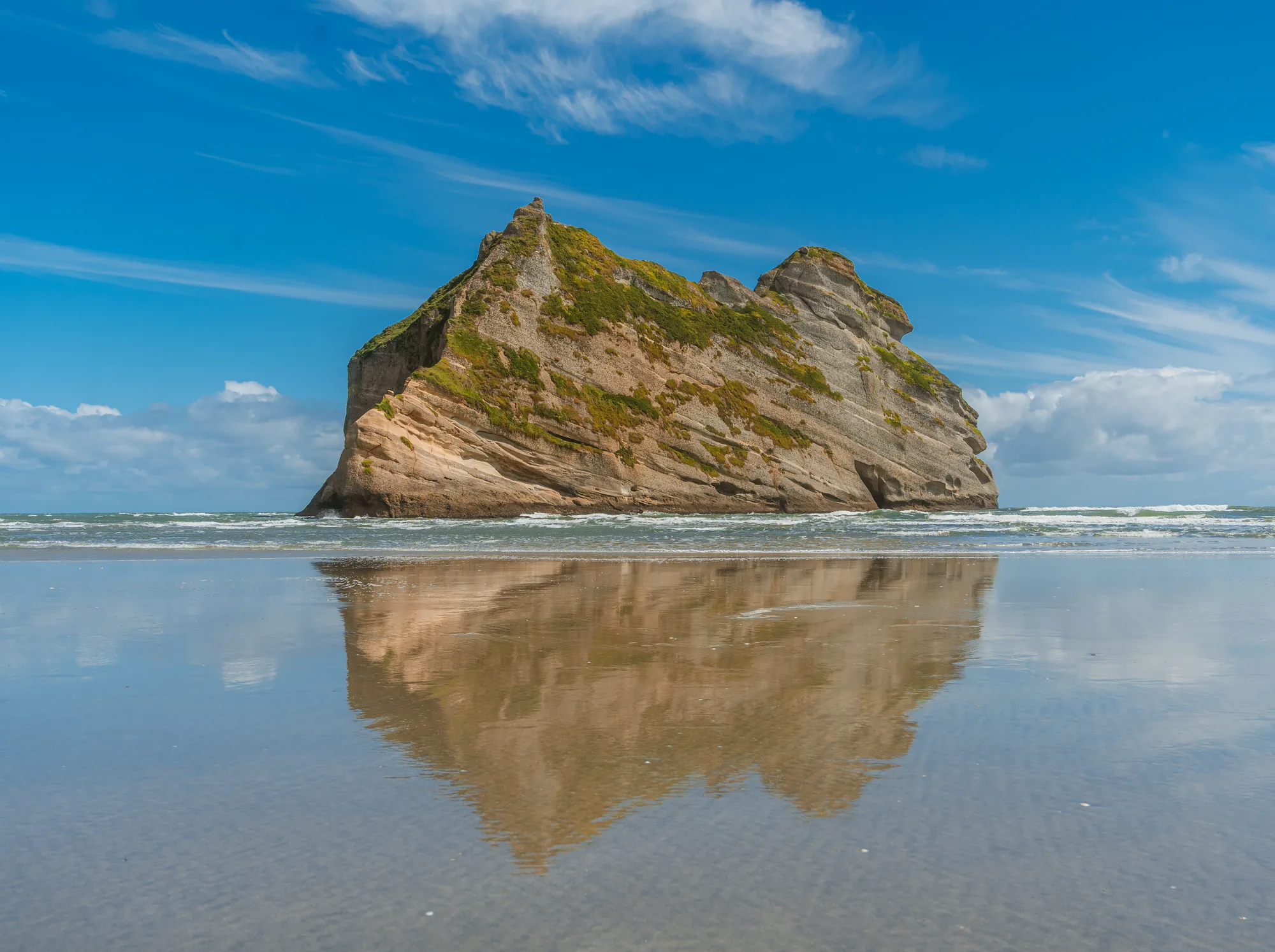 Wharariki Beach rock formations reflected in wet sand
